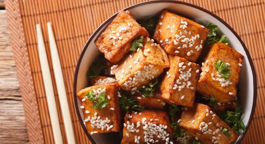 Knusprig gebratene Tofuwürfel mit Sesam und Petersilie in einer Schüssel. So schmeckt Tofu köstlich!