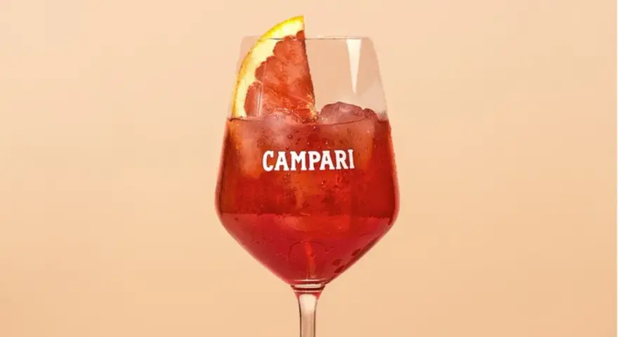 Ein Glas Campari mit Eis und einer Orangenscheibe. Entdecke die Vielfalt der Aperol Spritz Varianten!