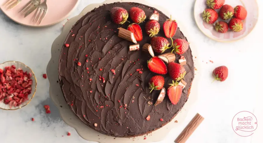 Eine köstliche Erdbeer Yogurette Torte mit Schokoladenglasur, frischen Erdbeeren und kleinen Schokostückchen.