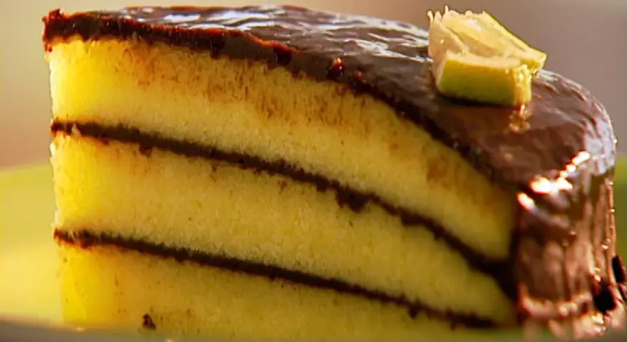 Ein saftiges Stück schoko zitronen kuchen mit Schokoladenglasur und einem Limettenschnitz.