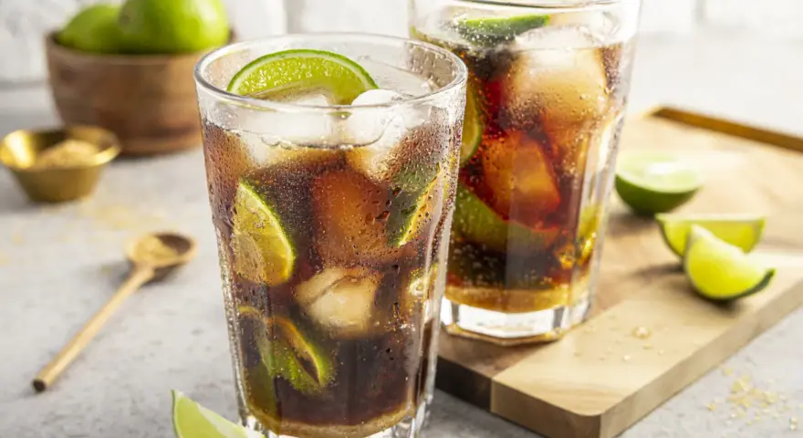 Zwei erfrischende Cuba Libre mit Eis und Limettenspalten, bereit zum Genuss.