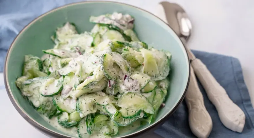 Frischer gurkensalat mit saurer sahne, Dill und roten Zwiebeln in einer Schüssel, bereit zum Servieren.