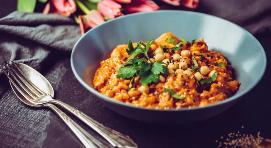 Herzhaftes Gericht mit Kichererbsen und Petersilie, verfeinert mit Garam Masala. Daneben liegen Gabel und Löffel.