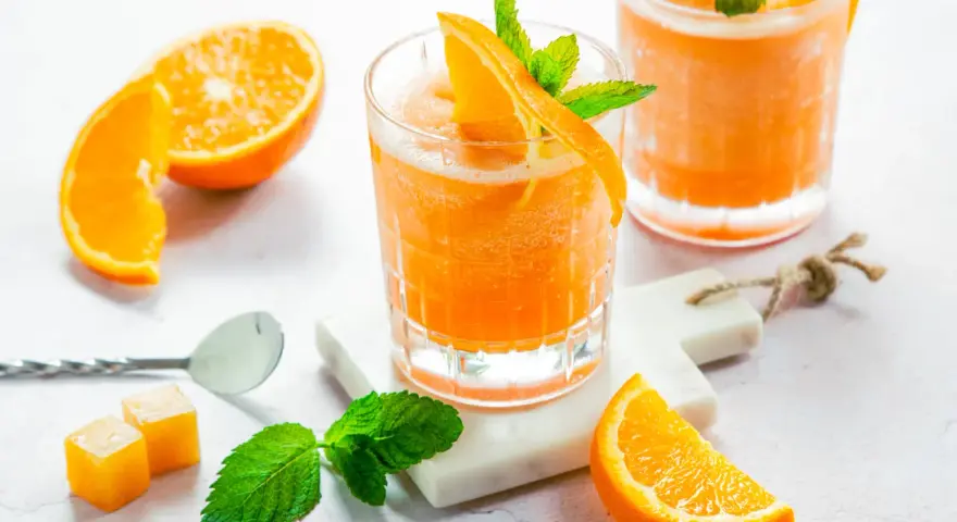 Erfrischender Aperol mit Orangensaft, garniert mit frischer Minze und Orangenspalten. Perfekt für einen sonnigen Nachmittag.
