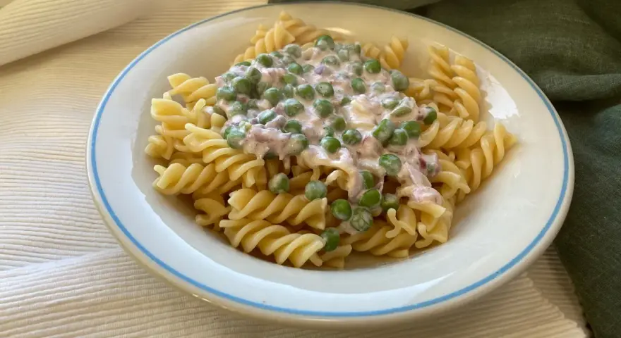 Fusilli-Pasta mit einer cremigen Sauce aus Erbsen und Speck, ein klassisches italienisches Gericht.