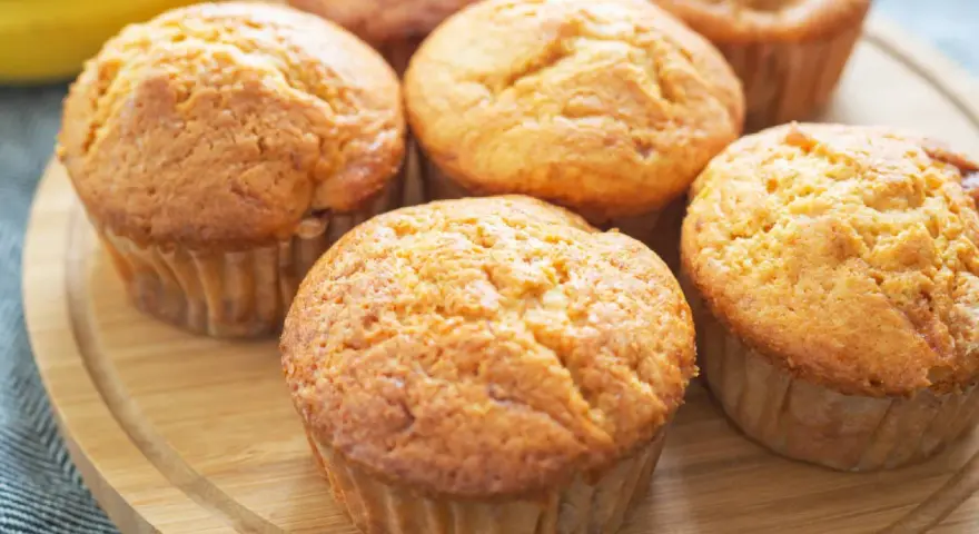 Goldbraune Bananen Quark Muffins auf einem Holzbrett, bereit zum Genießen.