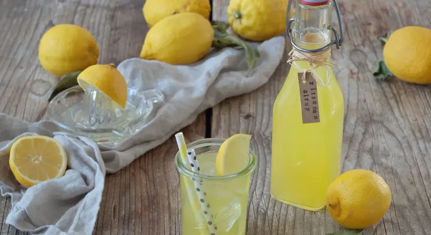 Frische Zitronen und selbstgemachter Zitronensirup in einer Flasche, bereit zum Genießen.