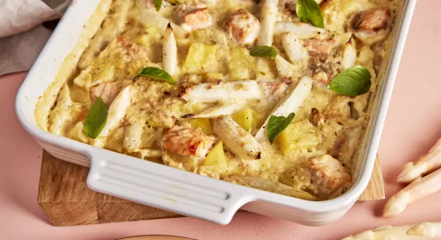 Ein köstlicher Spargel Lachs Auflauf in einer weißen Auflaufform, garniert mit Basilikum. Dazu frischer Spargel.