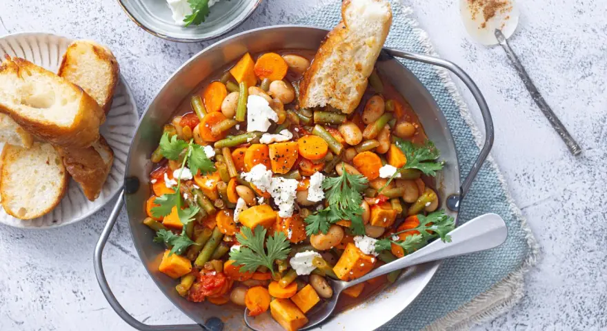 Herzhaftes Gericht mit Bohnen, Karotten und Süßkartoffeln, perfekt für Camping-Rezepte mit wenig Zutaten. Mit Feta und Brot serviert.