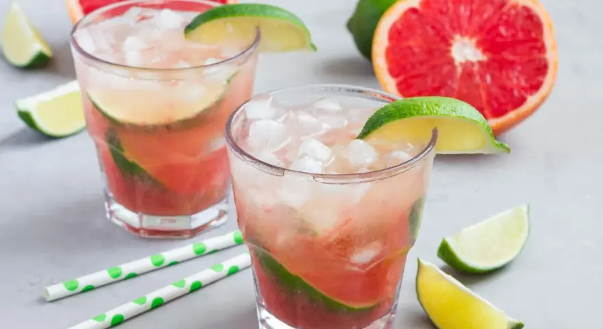 Erfrischender Aperol Paloma mit Grapefruit und Limette, garniert mit frischen Fruchtstücken und Eis.