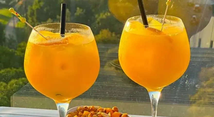 Zwei Gläser erfrischendes Aqua de Valencia mit Orangenscheiben und Eis, daneben eine Schale Nüsse.