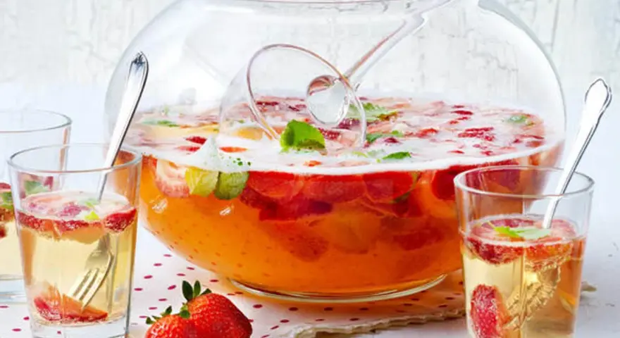 Erfrischendes Bowle-Rezept mit Erdbeeren und Minze in einer großen Glasbowle, bereit zum Servieren in Gläsern.