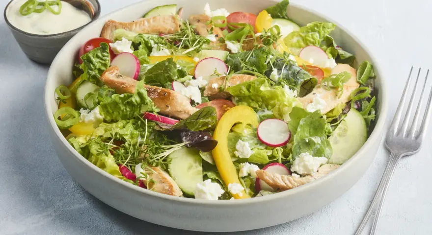 Frischer Salat mit Putenstreifen, Gurken, Radieschen, Tomaten, gelber Paprika und Feta. Dazu ein cremiges Dressing.