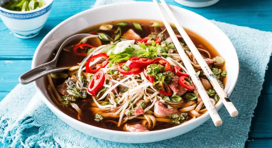 Eine Schüssel dampfendes Pho mit Rindfleisch, Nudeln, Sprossen und Chili. Was ist Pho? Ein aromatisches vietnamesisches Gericht.