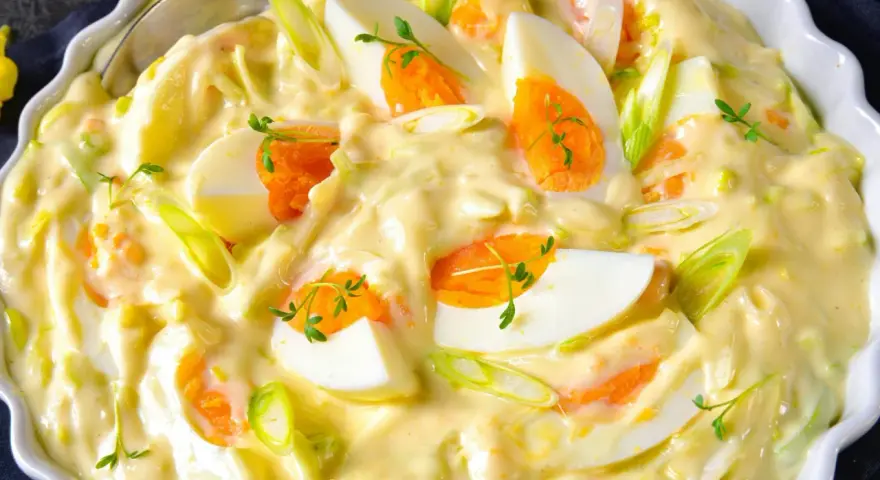 Cremiger Eiersalat mit Lauchzwiebeln und Kräutern, serviert in einer weißen Schüssel. Ein köstlicher Salat, der perfekt zu vielen Gerichten passt.