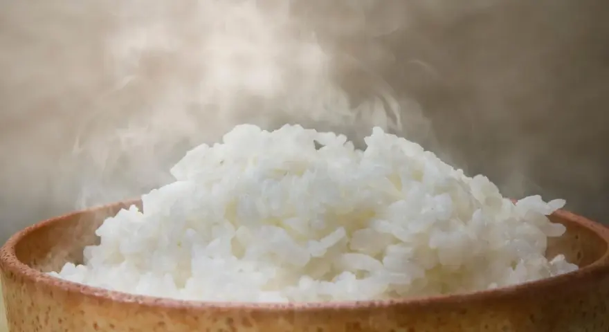 Dampfender Reis in einer Schale. Ein Beweis, dass Reis gesund ist und eine nahrhafte Mahlzeit darstellt.