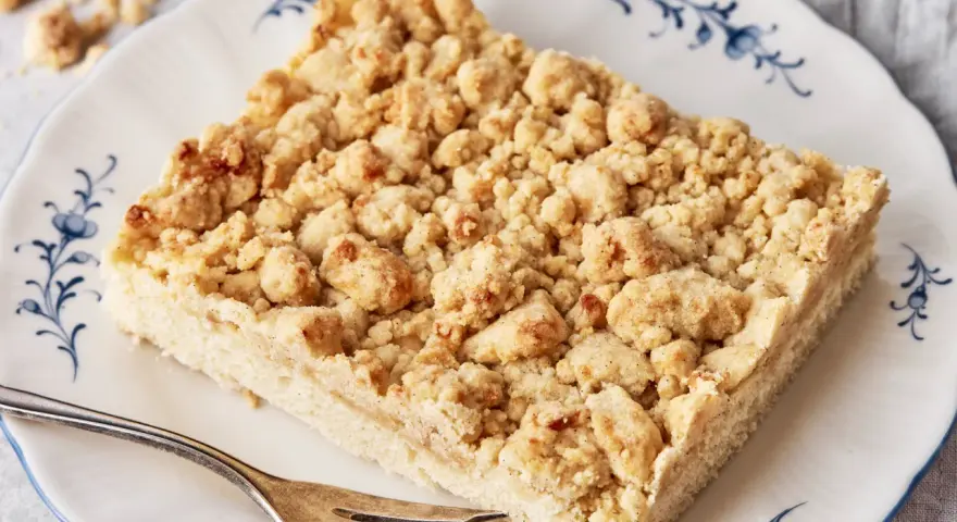 Ein Stück Streuselkuchen auf einem Teller mit Gabel. Dieses einfache Streuselkuchen Rezept gelingt immer!