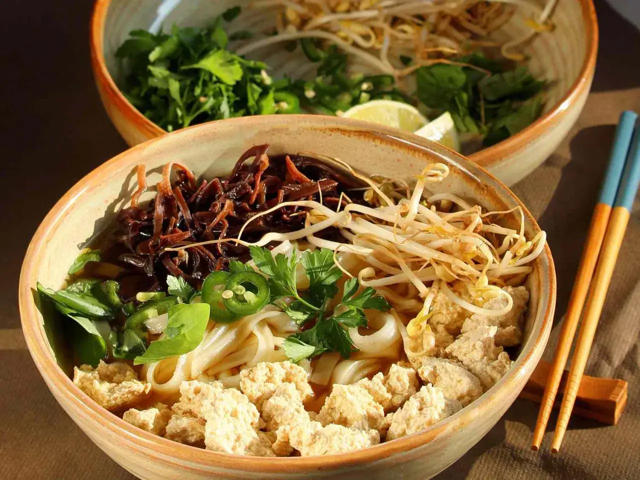 Eine Sch&uuml;ssel mit Pho, einer vietnamesischen Nudelsuppe, gef&uuml;llt mit Reisnudeln, Tofu, Sprossen, Kr&auml;utern und Jalape&ntilde;os.