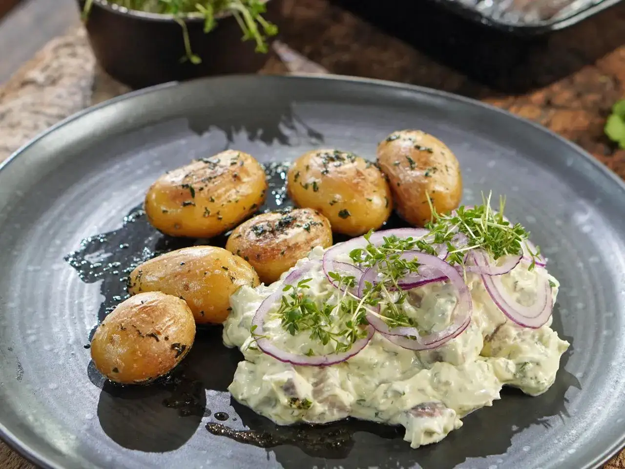 Matjes Hausfrauenart, Omas Rezept: zarte Matjesfilets in cremiger Sauce mit Zwiebeln und Kr&auml;utern, serviert mit kleinen Salzkartoffeln.