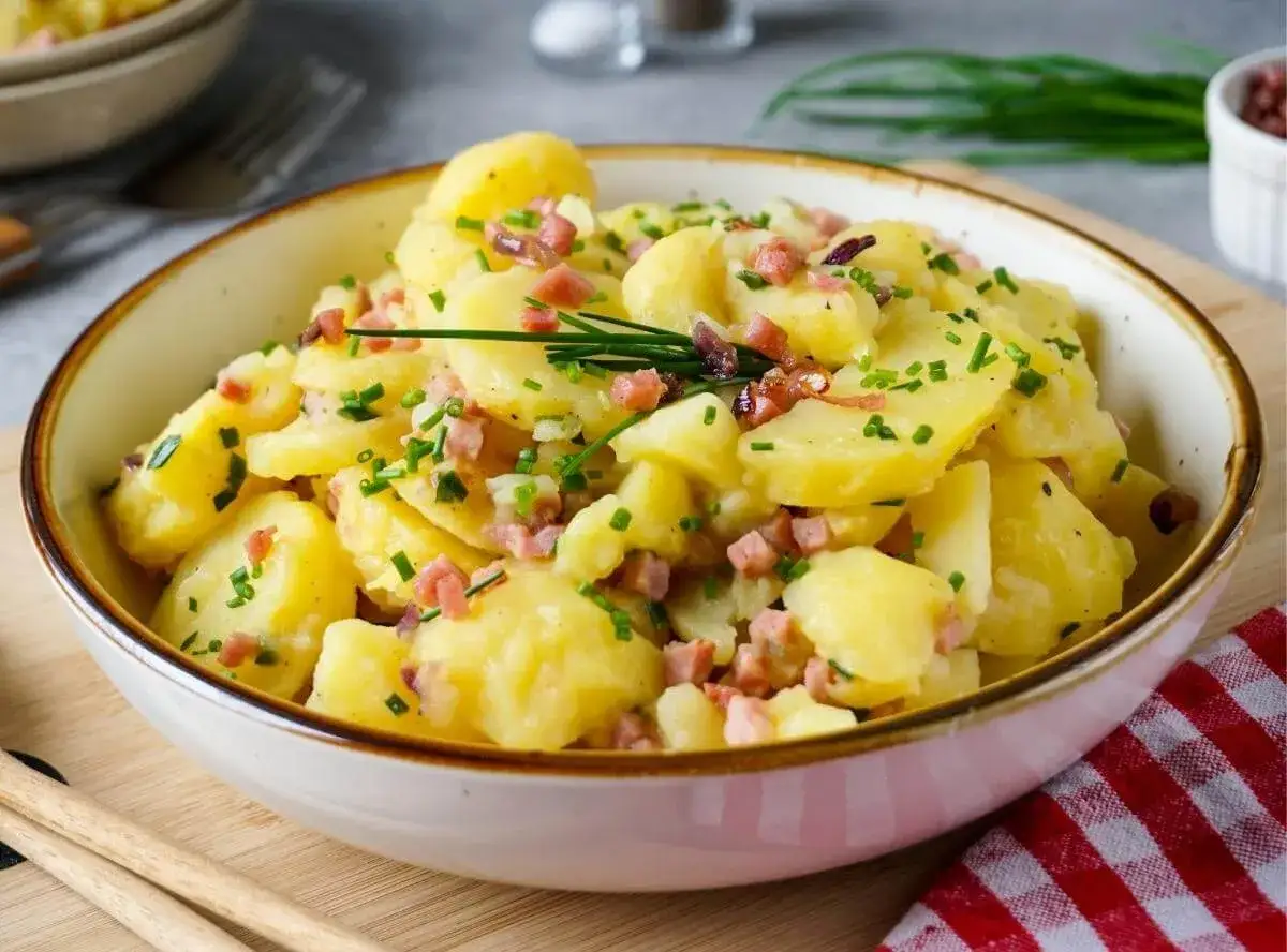 Ein Sch&uuml;ssel voller Kartoffelsalat mit Speck und Schnittlauch, bereit zum Genie&szlig;en.