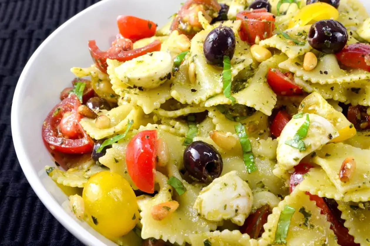 Farfalle Salat mit Pesto, Kirschtomaten, Mozzarella-Kugeln, schwarzen Oliven und Pinienkernen. Ein leichter und frischer Genuss.