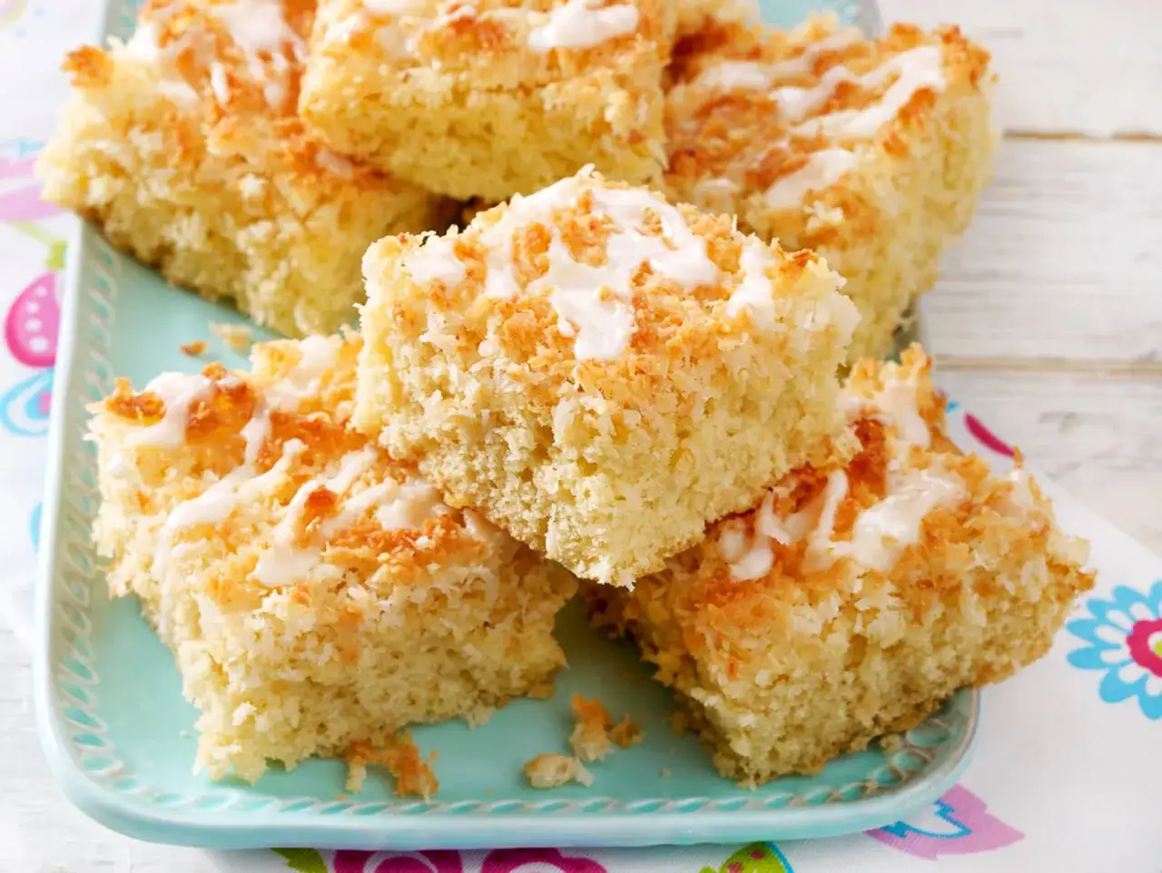 Saftiger Kuchen mit Kokosmilch, bestreut mit ger&ouml;steter Kokosnuss und einem Zuckerguss.