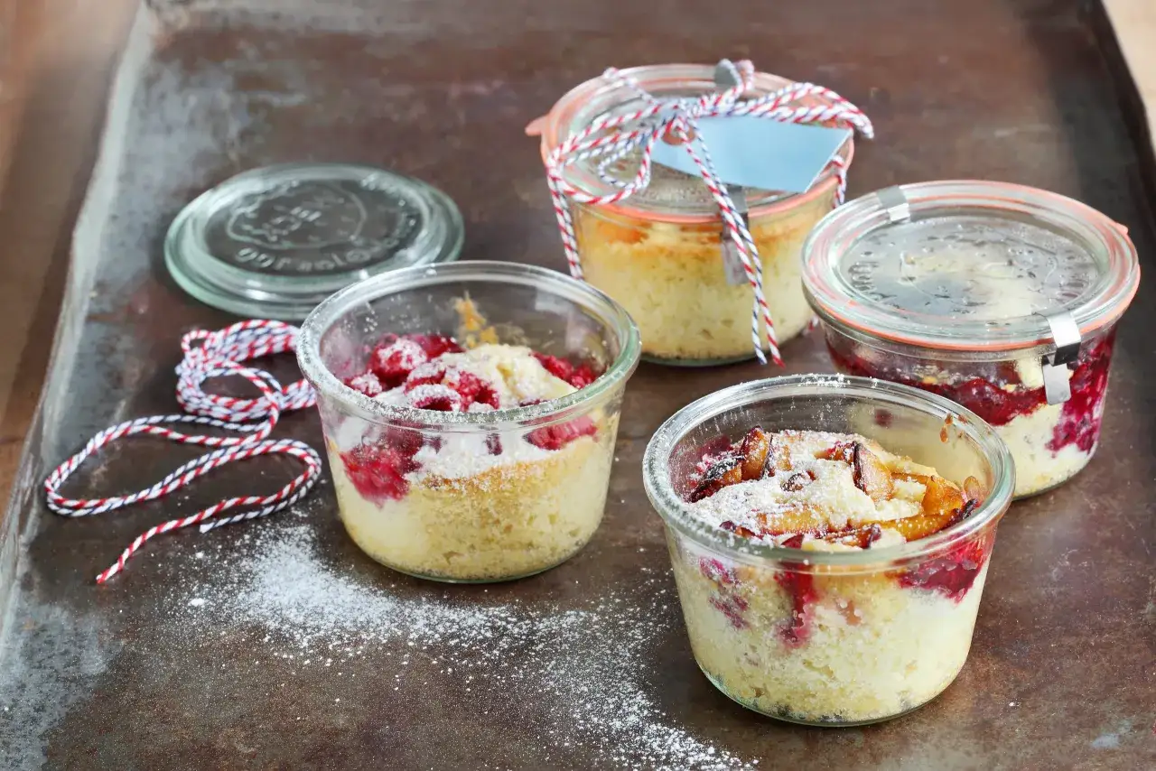 Vier leckere Kuchen im Glas mit Fr&uuml;chten und Puderzucker best&auml;ubt, bereit zum Genie&szlig;en.