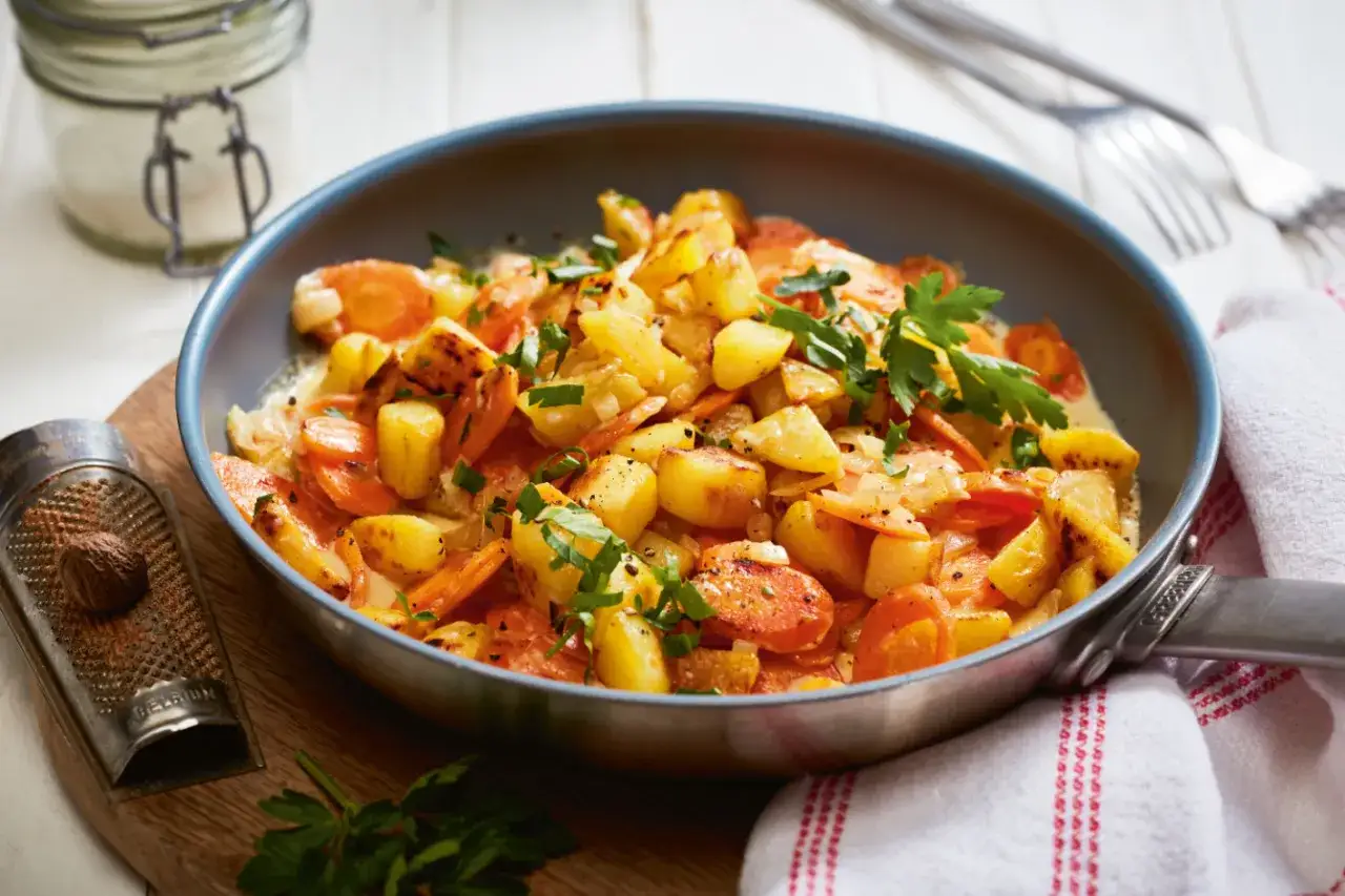 Kartoffeln mal anders: Ein herzhaftes Gericht aus goldbraunen Kartoffelw&uuml;rfeln und Karottenscheiben in cremiger Sauce, garniert mit frischer Petersilie.