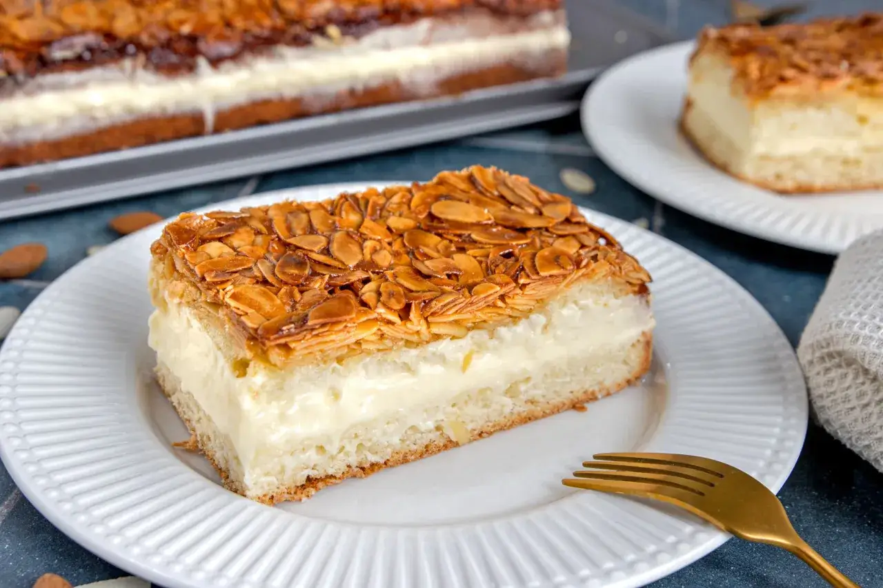 Ein Stück Bienenstich-Kuchen ohne Hefe, mit cremiger Füllung und karamellisierten Mandeln. Ein köstliches Rezept!