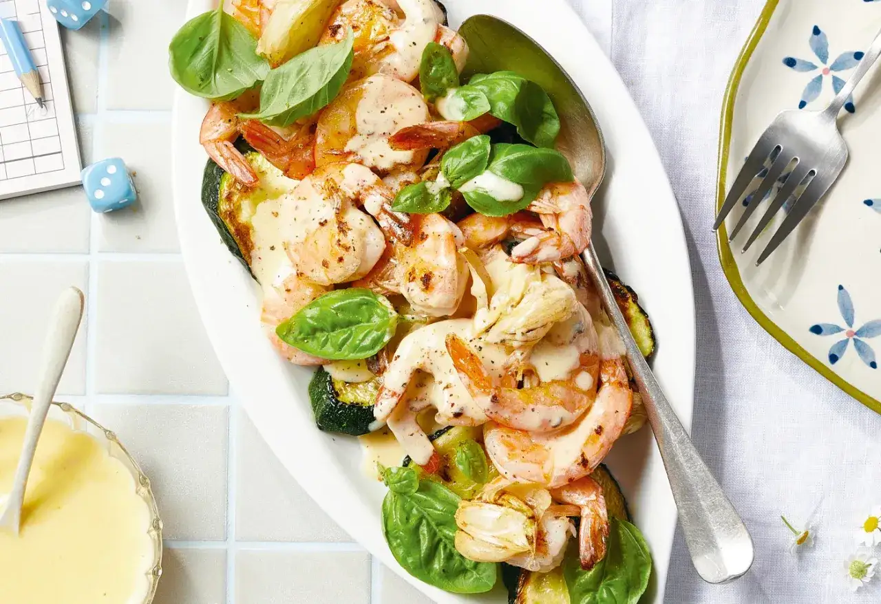 Gebratener Zucchini-Salat mit Garnelen und cremiger Sauce, garniert mit Basilikum. Ein köstliches Gericht, das Lust auf mehr macht.