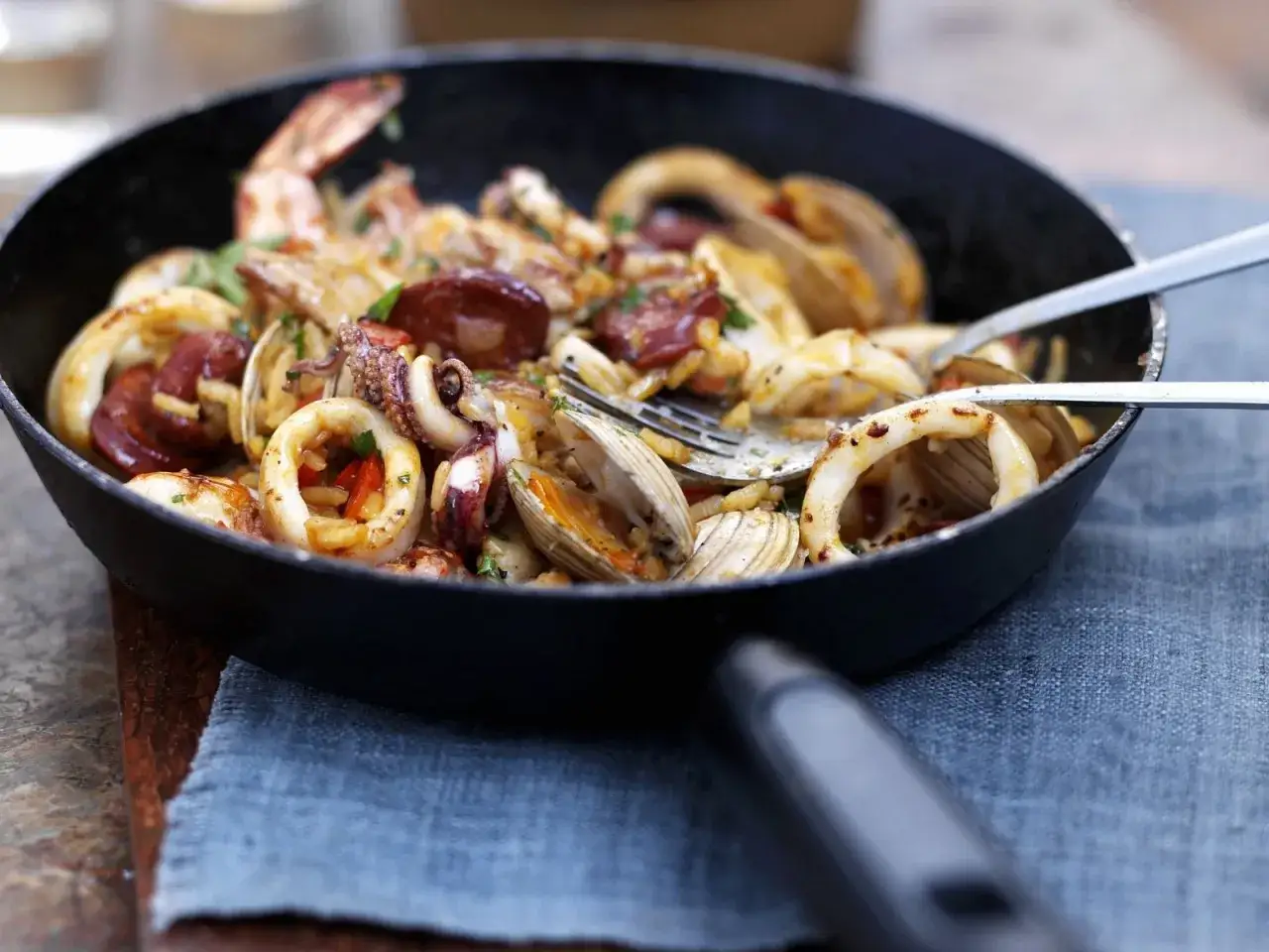 Eine k&ouml;stliche Paella mit Garnelen, Tintenfischringen, Muscheln und Chorizo in einer Pfanne.