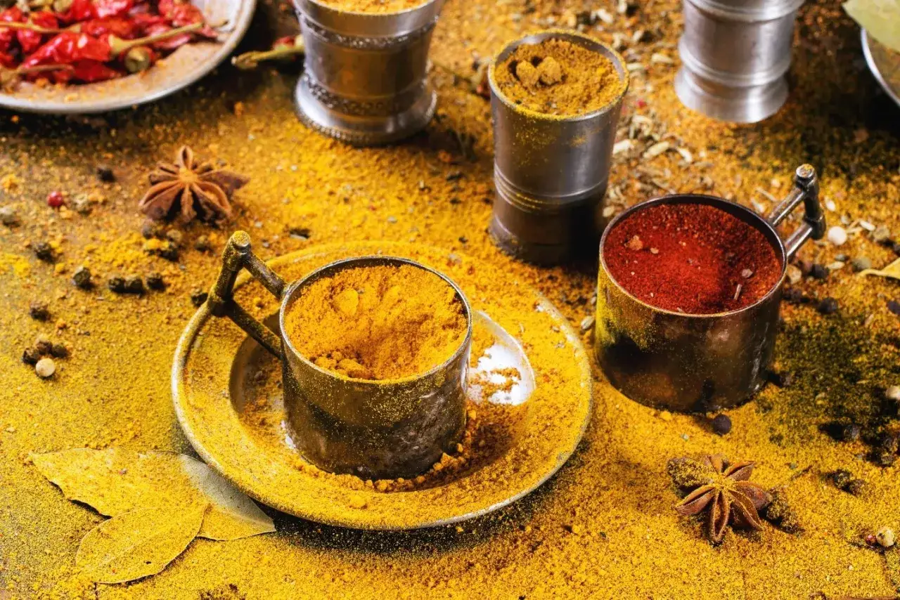 Bunte Gew&uuml;rze wie Kurkuma und Chili verstreut. Hier beginnt die Reise, woher kommt Curry. Sternanis und Lorbeerbl&auml;tter liegen zwischen den Pulvern.