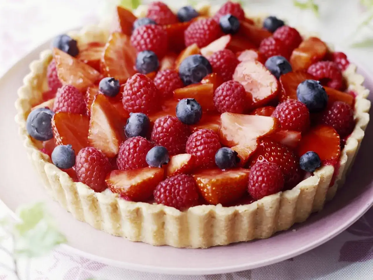 Ein schneller Kuchen ohne Backen mit frischen Erdbeeren, Himbeeren und Blaubeeren auf einem knusprigen Boden. Perfekt für heiße Tage!