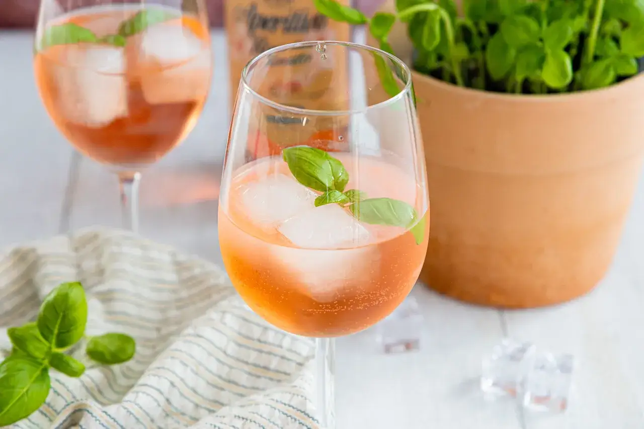 Erfrischender rosato spritz mit Eiswürfeln und Basilikum garniert, bereit für einen sonnigen Nachmittag.