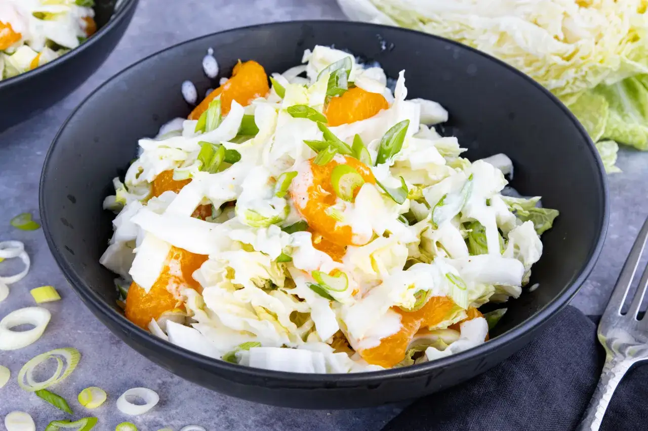 Frischer Chinakohlsalat mit saftigen Mandarinenstücken und Frühlingszwiebeln, beträufelt mit einem cremigen Dressing.