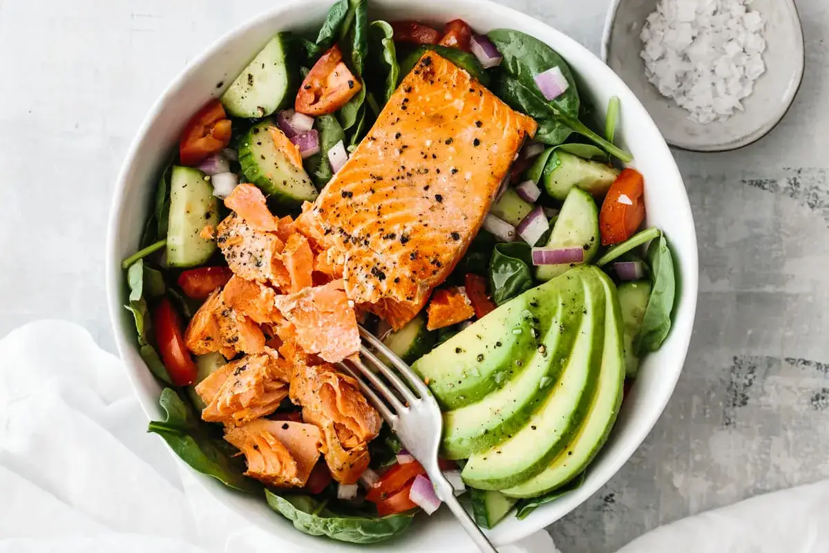 Ein frischer Salat mit Lachs und Avocado, garniert mit Tomaten, Gurken und roten Zwiebeln. Perfekt f&uuml;r eine leichte Mahlzeit.