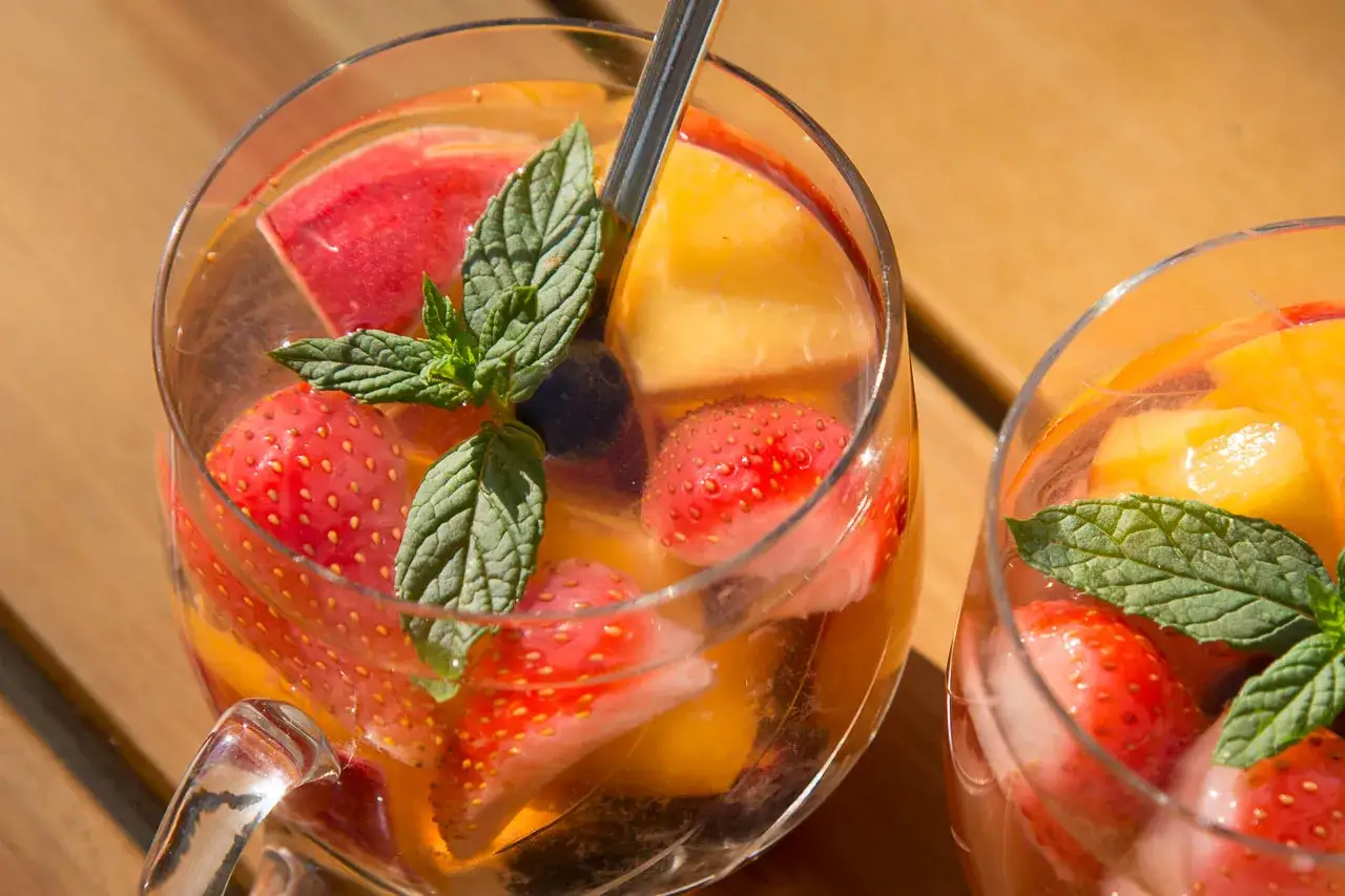 Erfrischende alkoholfreie Bowle mit Erdbeeren, Pfirsichen und Minze in einem Glas.