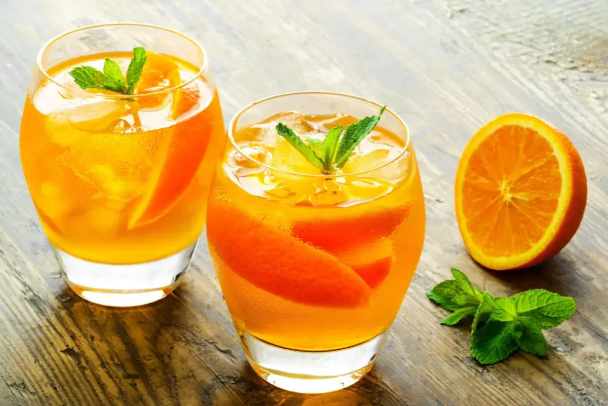 Erfrischendes Aqua de Valencia mit Orangenscheiben und Minze, serviert auf einem Holztisch.