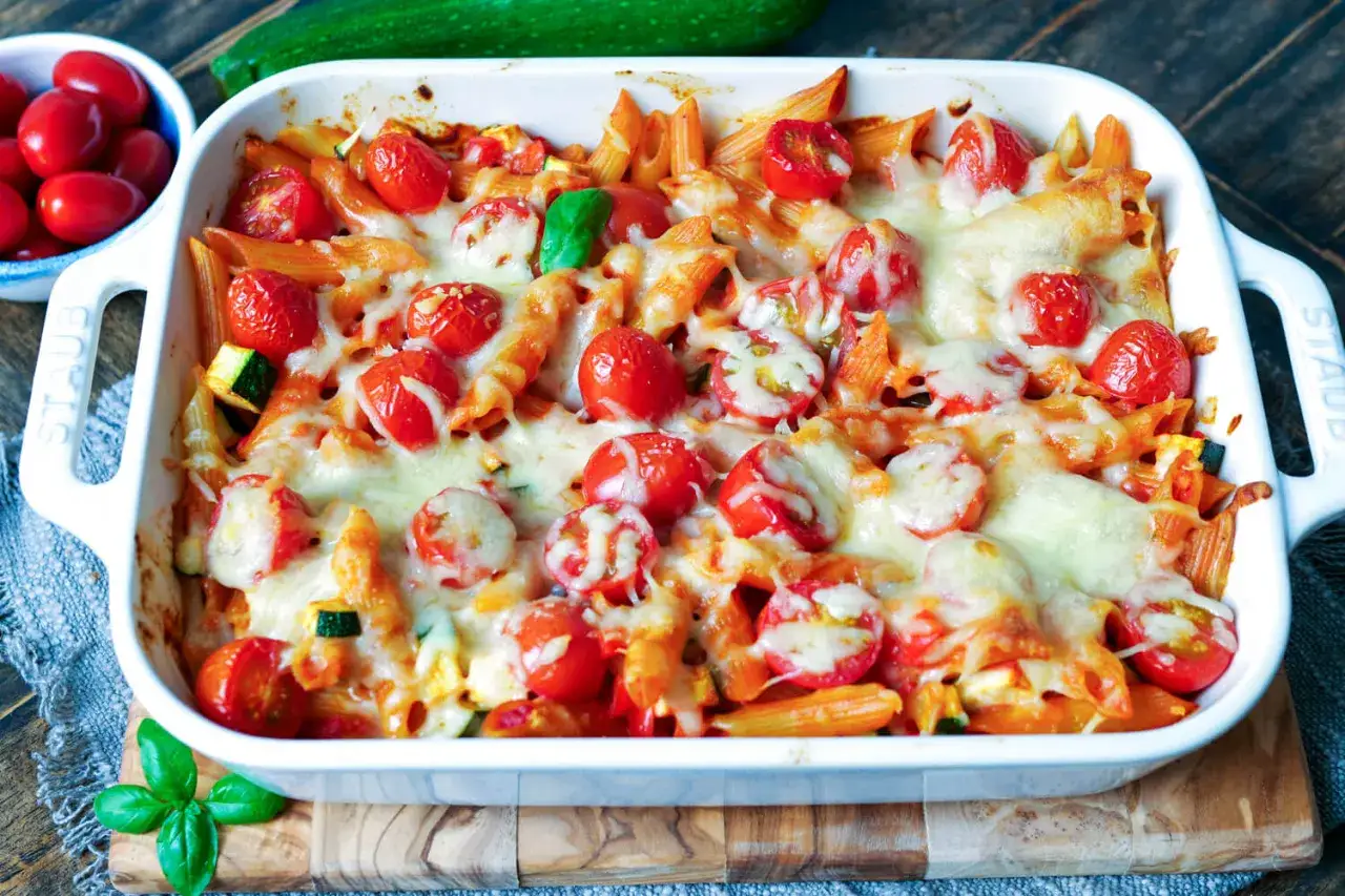 Nudelauflauf ohne Vorkochen mit Kirschtomaten und geschmolzenem K&auml;se in einer wei&szlig;en Auflaufform.