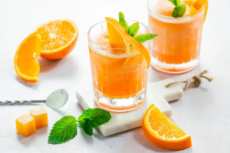 Erfrischender Aperol mit Orangensaft, garniert mit frischer Minze und Orangenspalten. Perfekt für einen sonnigen Nachmittag.